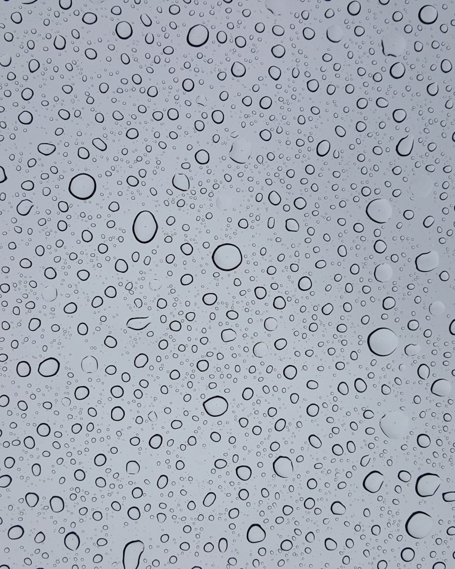 Close-up macro photograph of water droplets beaded on a glass surface.